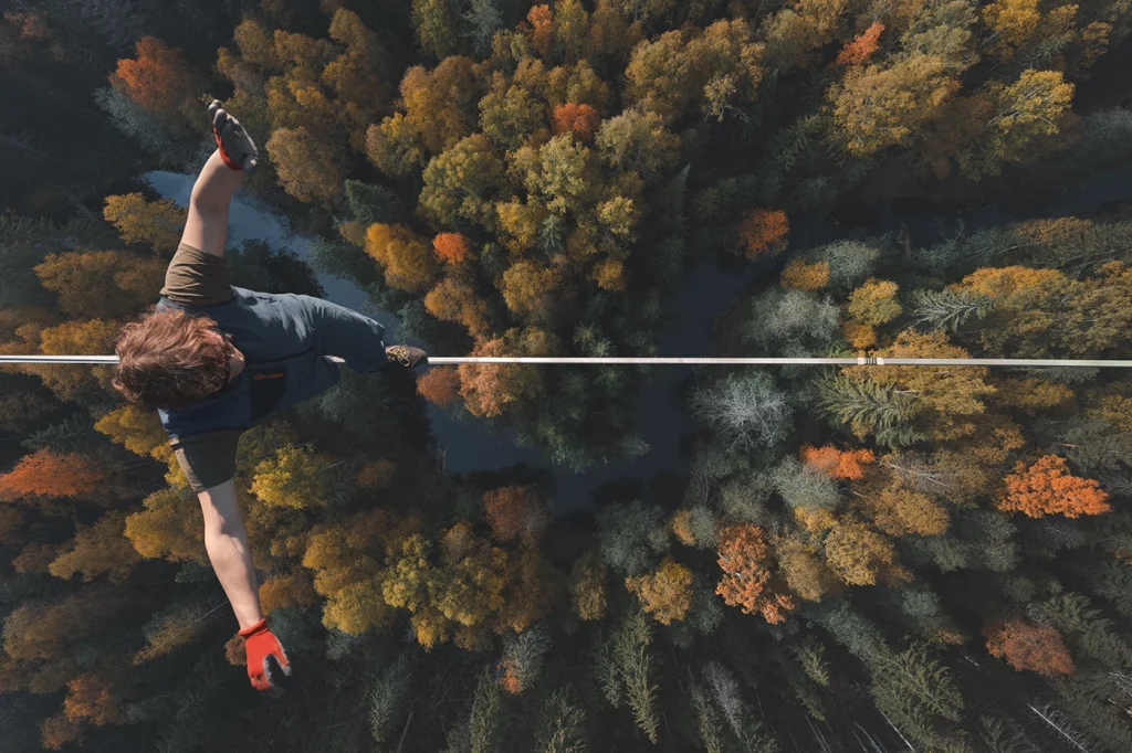 A man balancing on a rope or wire high above trees